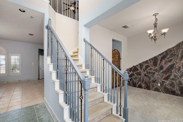 stairs with a chandelier, visible vents, baseboards, and tile patterned floors