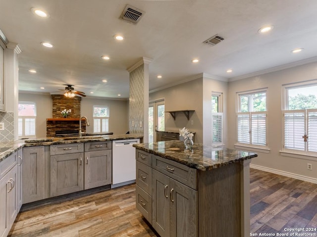 kitchen with white dishwasher, visible vents, dark stone counters, and crown molding