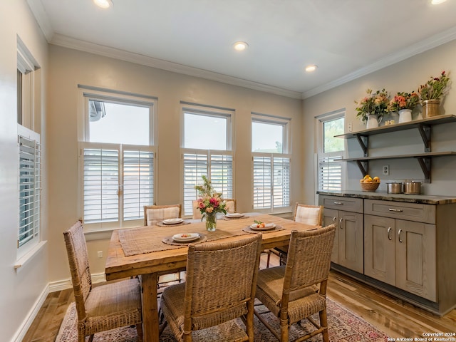 dining area with light wood-type flooring, crown molding, baseboards, and recessed lighting