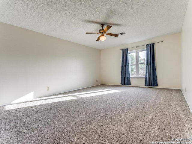 carpeted empty room with visible vents, ceiling fan, and a textured ceiling