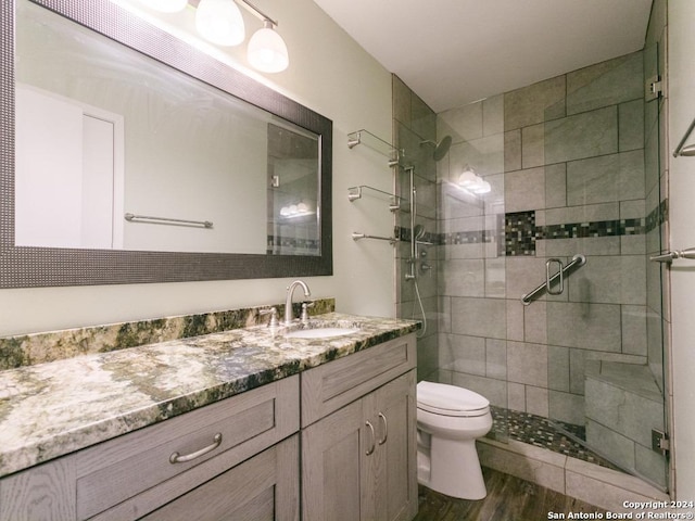 bathroom with toilet, a shower stall, wood finished floors, and vanity