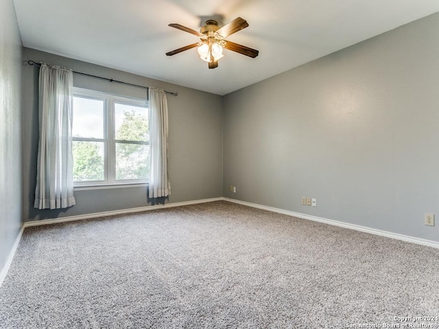 carpeted spare room with a ceiling fan and baseboards