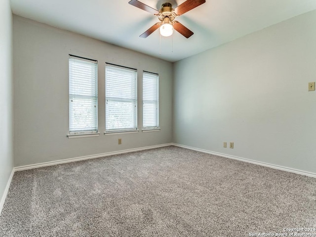 carpeted spare room featuring a ceiling fan and baseboards