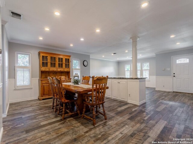 dining space featuring a healthy amount of sunlight, ornate columns, dark wood finished floors, and wainscoting