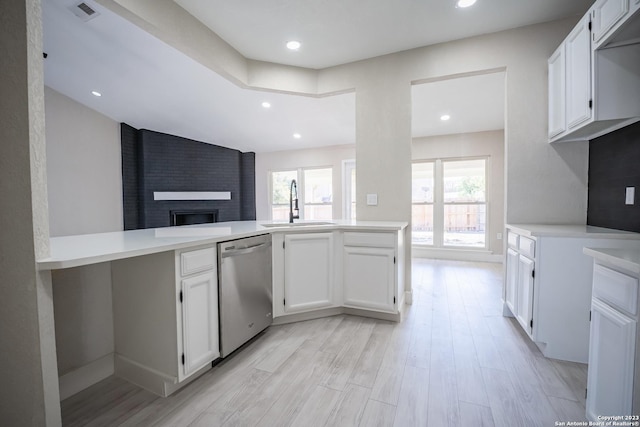 kitchen with sink, white cabinetry, kitchen peninsula, dishwasher, and light hardwood / wood-style floors