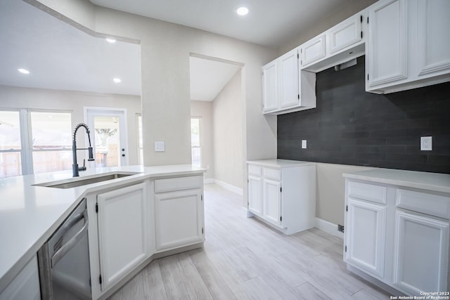 kitchen featuring a wealth of natural light, dishwasher, white cabinetry, sink, and decorative backsplash