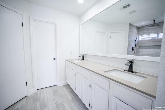 bathroom with vanity, wood-type flooring, and tiled shower