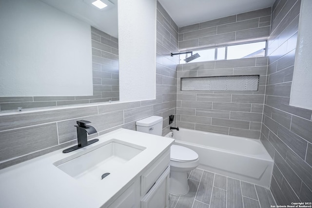 full bathroom featuring tiled shower / bath combo, vanity, tile walls, and toilet