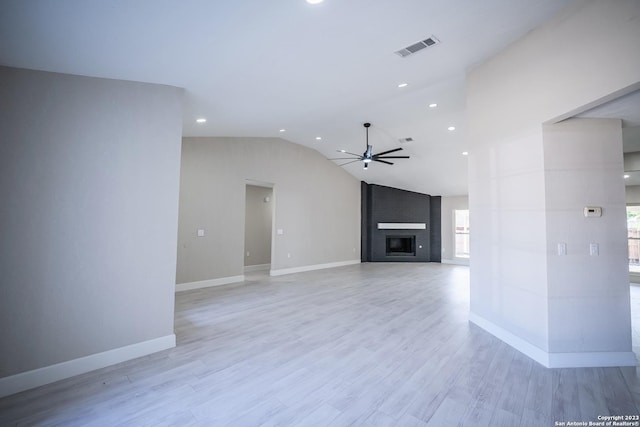 unfurnished living room with ceiling fan, a large fireplace, vaulted ceiling, and light hardwood / wood-style floors