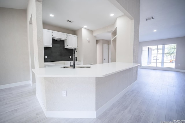 kitchen featuring sink, white cabinetry, tasteful backsplash, light hardwood / wood-style floors, and a kitchen island