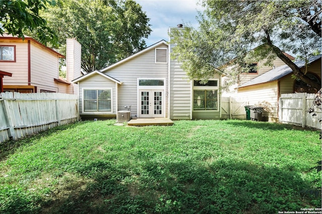 back of property with french doors, a yard, and central AC