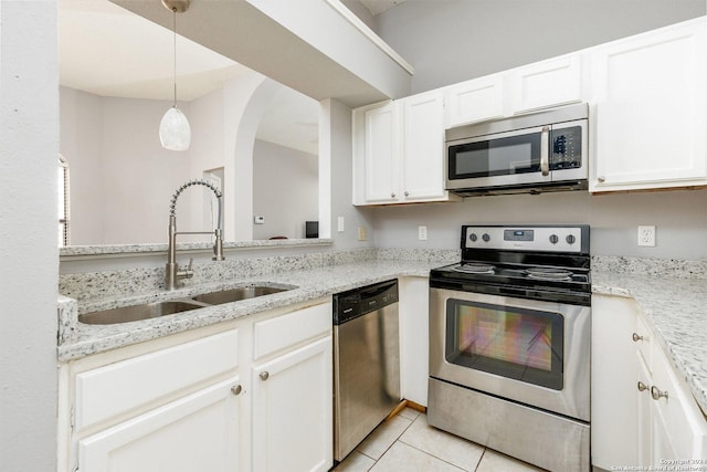 kitchen featuring appliances with stainless steel finishes, decorative light fixtures, sink, white cabinets, and light stone countertops