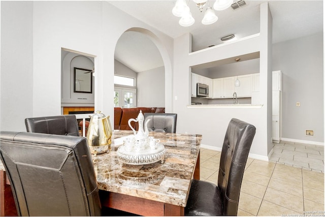 tiled dining room with lofted ceiling, sink, and a chandelier