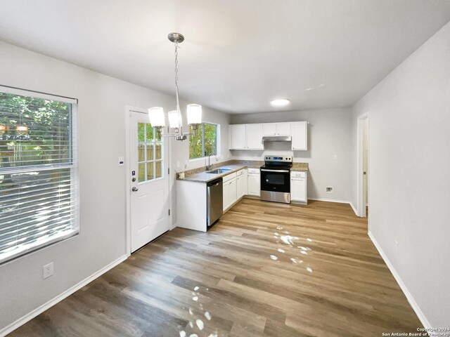 kitchen with hanging light fixtures, white cabinets, sink, appliances with stainless steel finishes, and light hardwood / wood-style flooring