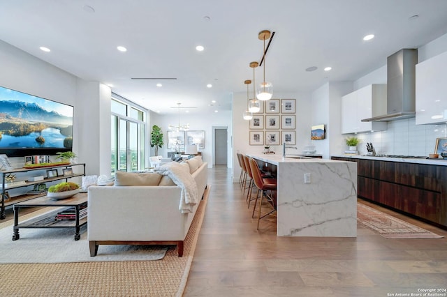 kitchen featuring light wood-type flooring, white cabinets, wall chimney exhaust hood, decorative backsplash, and dark brown cabinetry