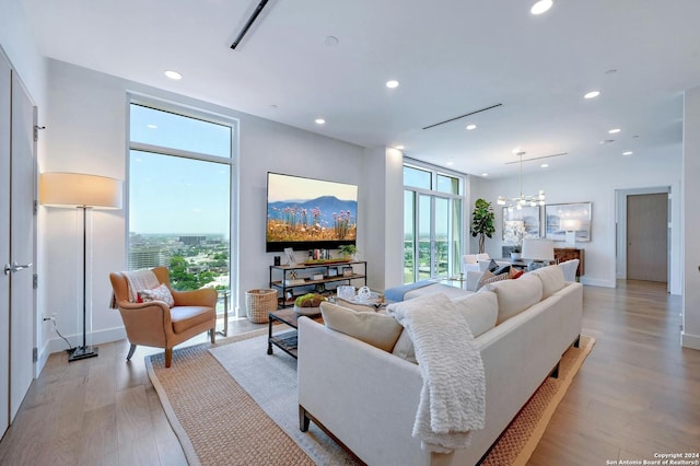 living room with a wall of windows, light hardwood / wood-style flooring, and a chandelier