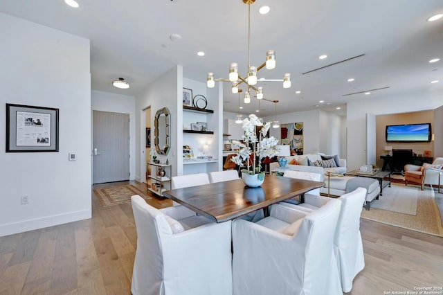 dining space with light hardwood / wood-style flooring and an inviting chandelier