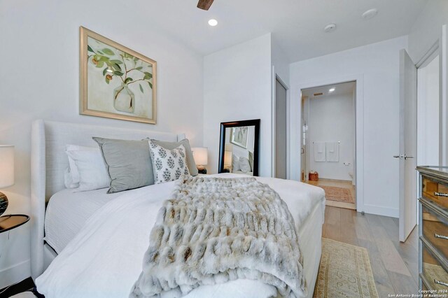 bedroom with ensuite bath, light wood-type flooring, and ceiling fan