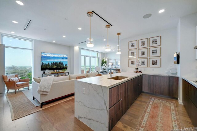 kitchen with light hardwood / wood-style floors, light stone countertops, sink, and kitchen peninsula