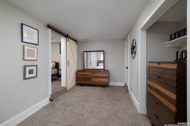 hallway featuring a barn door and light colored carpet