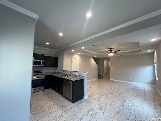 kitchen featuring ceiling fan, a tray ceiling, light stone counters, appliances with stainless steel finishes, and kitchen peninsula