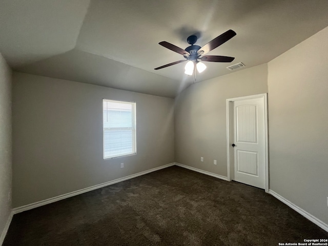 spare room with dark carpet, ceiling fan, and lofted ceiling