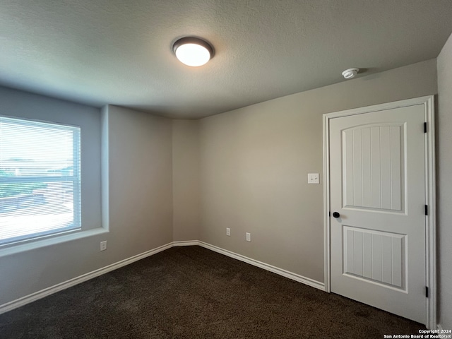 empty room featuring dark colored carpet