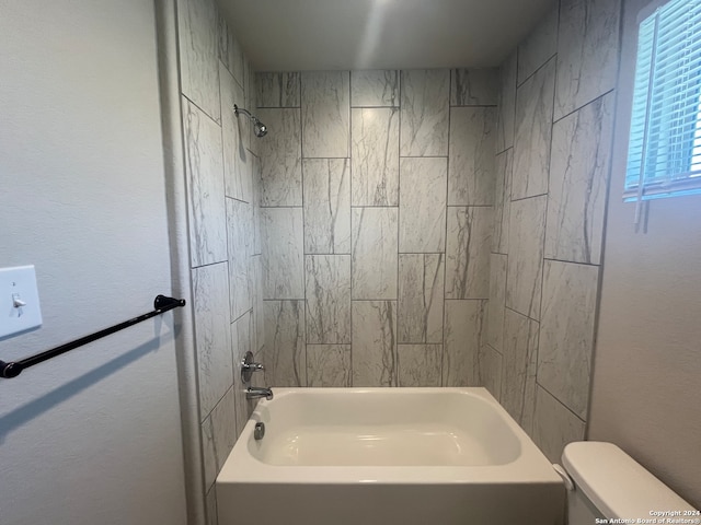 bathroom featuring tiled shower / bath combo and toilet