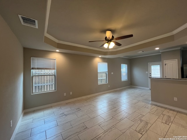 tiled spare room featuring a raised ceiling, crown molding, and ceiling fan