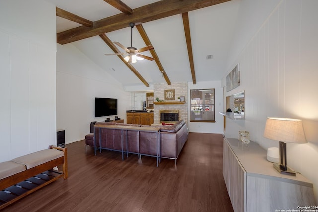 living room featuring dark wood-type flooring, ceiling fan, a fireplace, and beam ceiling