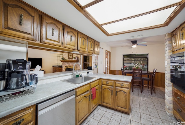 kitchen with sink, black oven, dishwasher, ceiling fan, and kitchen peninsula