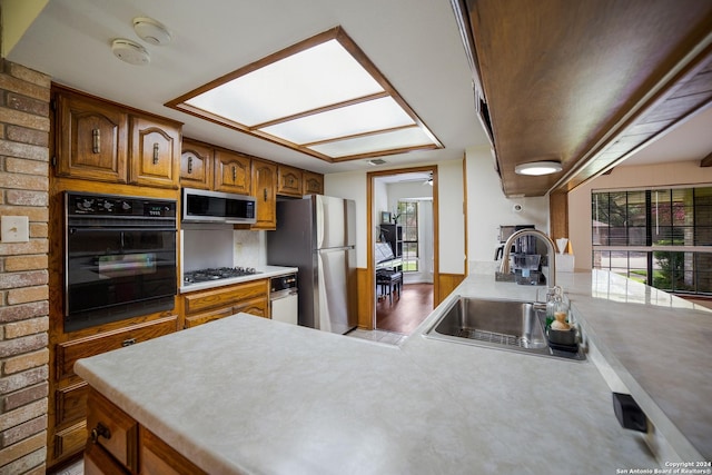 kitchen featuring hardwood / wood-style floors, a skylight, sink, decorative backsplash, and stainless steel appliances