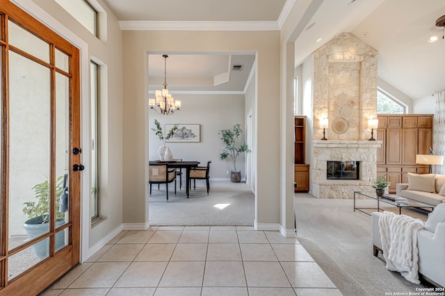 carpeted foyer entrance featuring a stone fireplace and a chandelier