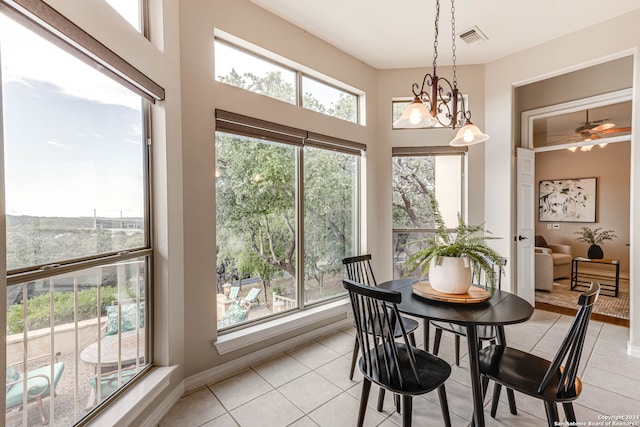 tiled dining room with ceiling fan with notable chandelier and a healthy amount of sunlight