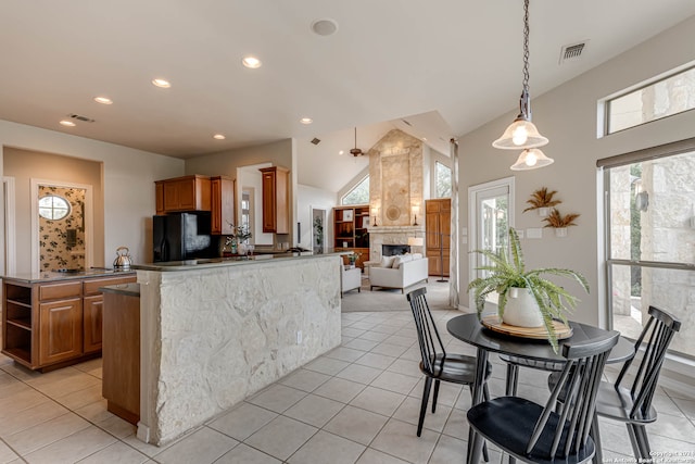 kitchen featuring hanging light fixtures, kitchen peninsula, high vaulted ceiling, black refrigerator, and light tile patterned flooring