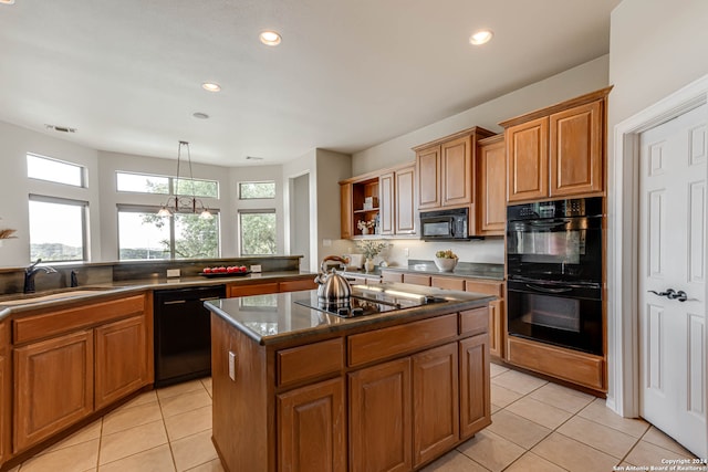 kitchen featuring a center island, decorative light fixtures, sink, black appliances, and light tile patterned flooring