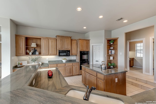 kitchen featuring black appliances, light tile patterned floors, a center island, and sink