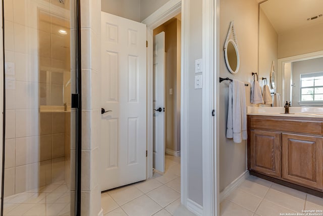 bathroom with a shower with door, vanity, and tile patterned flooring