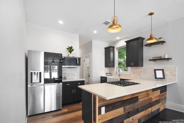 kitchen featuring decorative backsplash, kitchen peninsula, and stainless steel refrigerator with ice dispenser