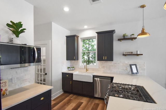 kitchen with appliances with stainless steel finishes, dark hardwood / wood-style floors, sink, backsplash, and hanging light fixtures