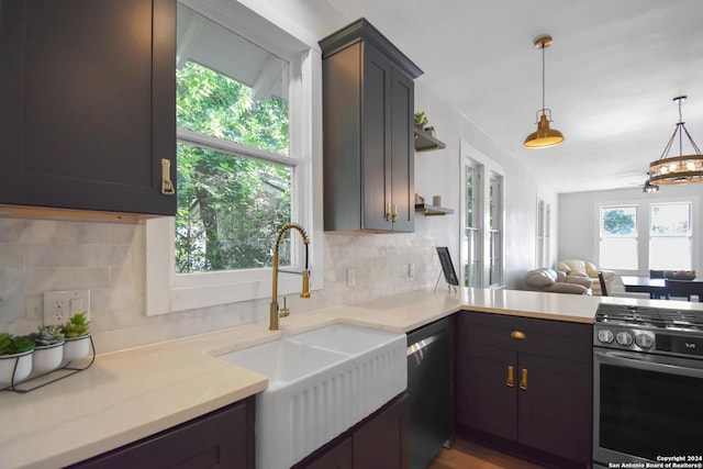 kitchen featuring stainless steel gas stove, tasteful backsplash, sink, dishwashing machine, and hanging light fixtures