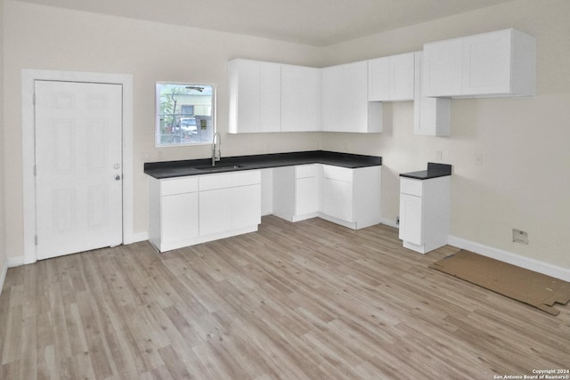 kitchen with white cabinetry, sink, and light hardwood / wood-style floors