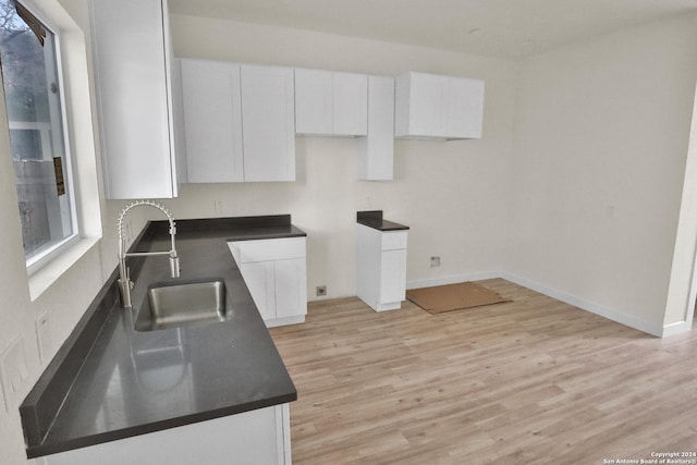 kitchen featuring white cabinetry, sink, and light hardwood / wood-style flooring