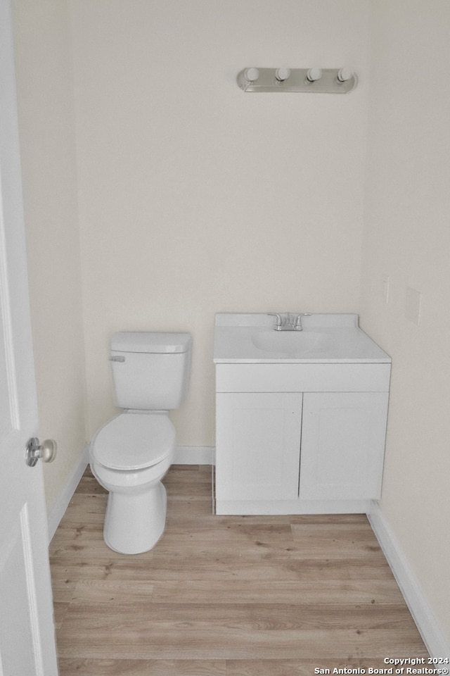 bathroom featuring wood-type flooring, toilet, and vanity