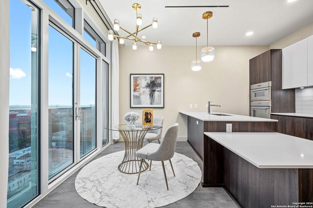 kitchen with dark wood-type flooring, stainless steel gas cooktop, wall chimney exhaust hood, decorative backsplash, and sink