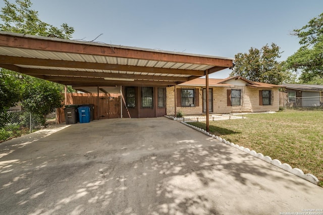 view of front of home with brick siding, fence, concrete driveway, a carport, and a front lawn