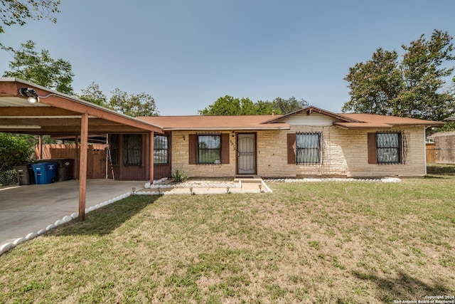 ranch-style home featuring brick siding, fence, a carport, driveway, and a front lawn