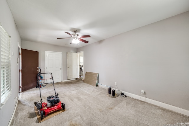 workout room featuring ceiling fan, a wealth of natural light, and light colored carpet