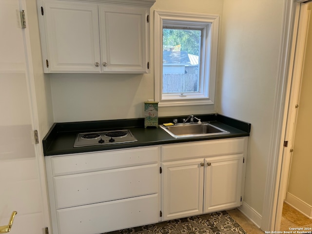 kitchen featuring white stovetop, white cabinets, and sink