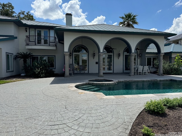 back of property with a balcony, a patio, a swimming pool with hot tub, and french doors